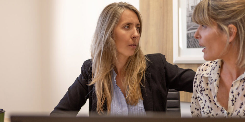 Two women looking concerned and having a serious conversation at work.