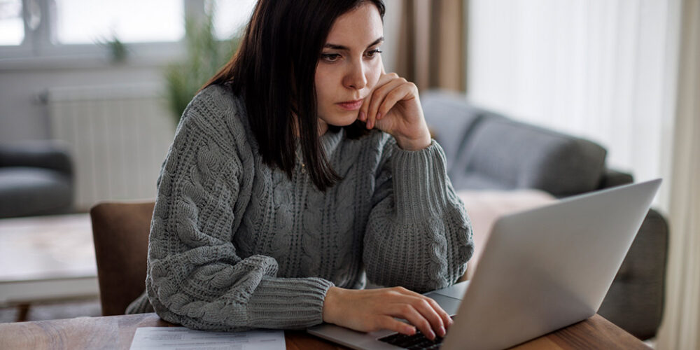 Woman on a laptap concentrating and looking serious.