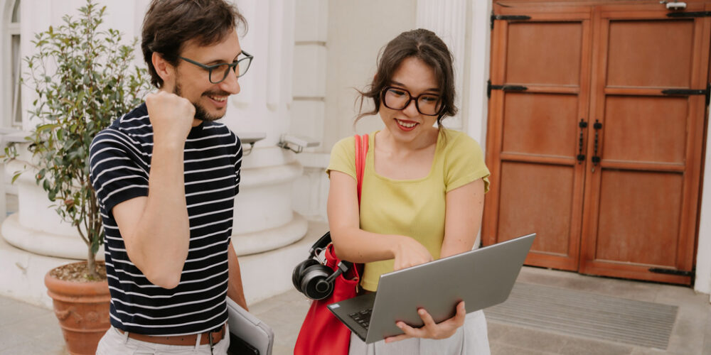 Woman smiling while showing a smiling man something on a laptop.