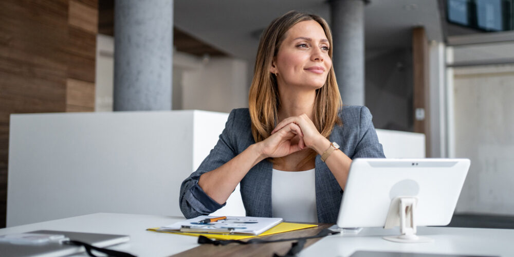 A professional woman sitting at her desk looking content